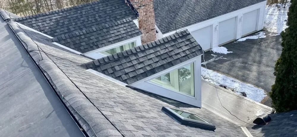 New gray shingle roof with gabled dormers on a white house