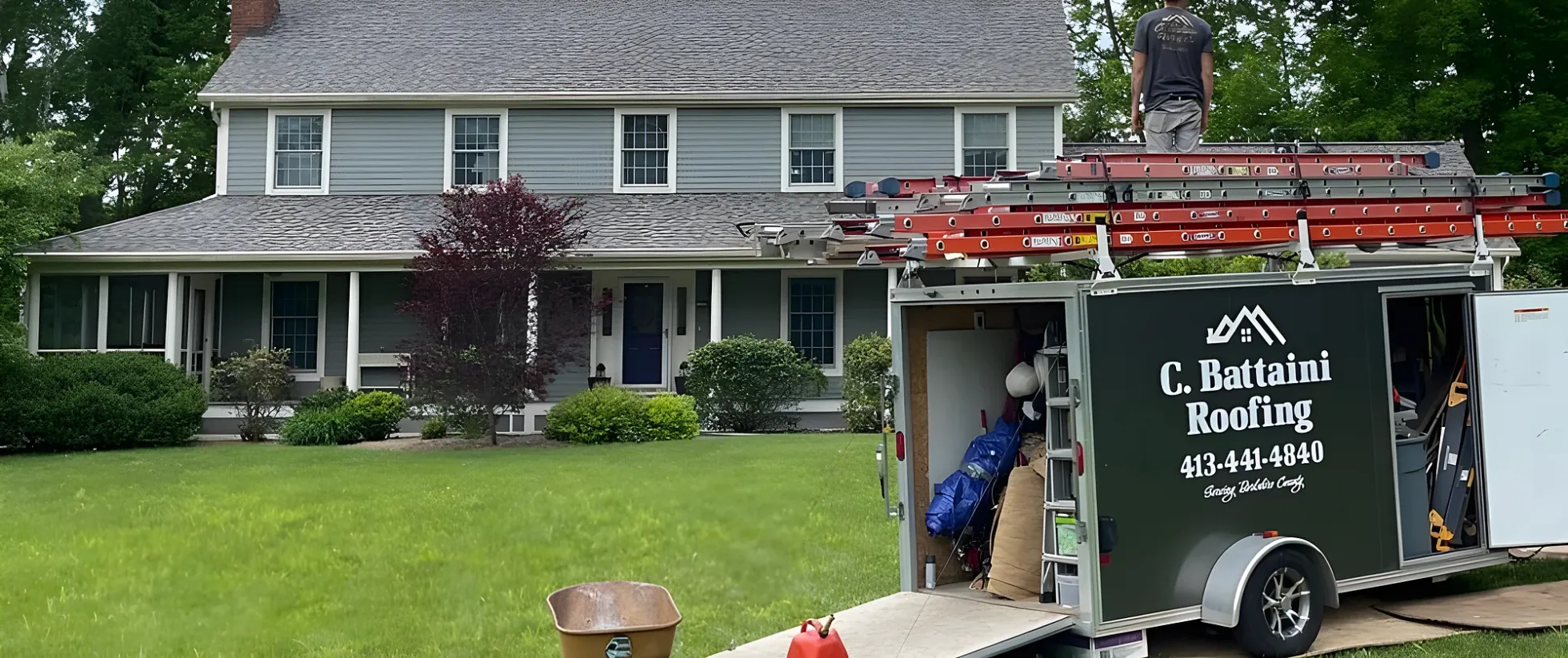 C. Battaini Roofing equipment trailer parked on the lawn at a colonial home during a roofing job